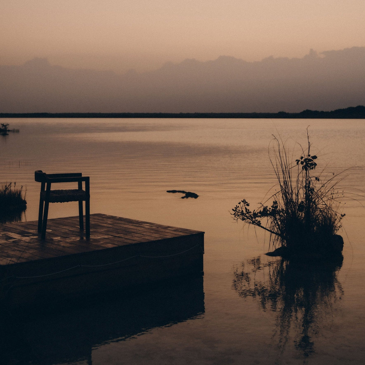 Un lac à la tombée du jour, une chaise sur un ponton